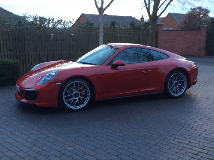 991 GTS Must haves - Page 203 - 911/Carrera GT - PistonHeads - The image features a red sports car parked on a brick driveway. The vehicle is positioned in the foreground, with its hood propped up by two blocks, revealing the engine. It appears to be a high-performance model given the wide stance and large intakes at the back. The car's design includes a prominent rear wing and multi-spoke wheels, contributing to its sporty aesthetic. In the background, there is a glimpse of residential architecture with a brick wall and what seems to be a house. The style of the image is a clear, well-lit photograph, possibly for the purposes of showcasing the car or for an advertisement.