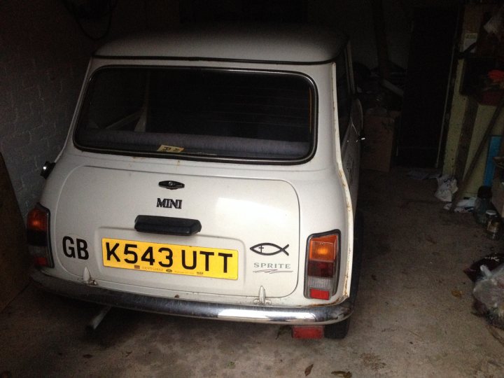 What's it worth? - Page 1 - Classic Minis - PistonHeads - This image depicts a small vintage white car parked in a garage. The back of the car displays a yellow license plate with the registration K543 UTT. Additionally, there is a fish-shaped logo on the back door which appears to be a decal from the brand "Sprit". The car's body shows some signs of wear with visible paint damage and faded areas, indicating it's likely an older model.