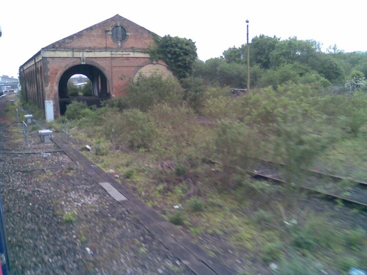 Exploring Pistonheads Abandoned Stuff Machines Urban - The image showcases a wooden bridge and tracks that appear to be in disuse or possibly not in use at this moment. The bridge, which seems made of old wood, is arched and serves as the pier leading out to the tracks. The tracks, devoid of any rails visible, are set against the backdrop of overgrown vegetation and a cloudy sky. It is a tranquil scene that exudes an air of abandonment.