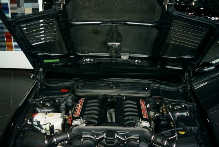 Show Pistonheads Bmw - The image depicts the open hood of a luxury car. The engine compartment houses a complex array of components. The engine is dominated by a large metal frame, and there is evidence of thermal head wrapping around the edges of the open hood. The surrounding area of the car is dimly lit, contrasting with the brightness of the engine and letting the viewer focus on the mechanics of the vehicle.