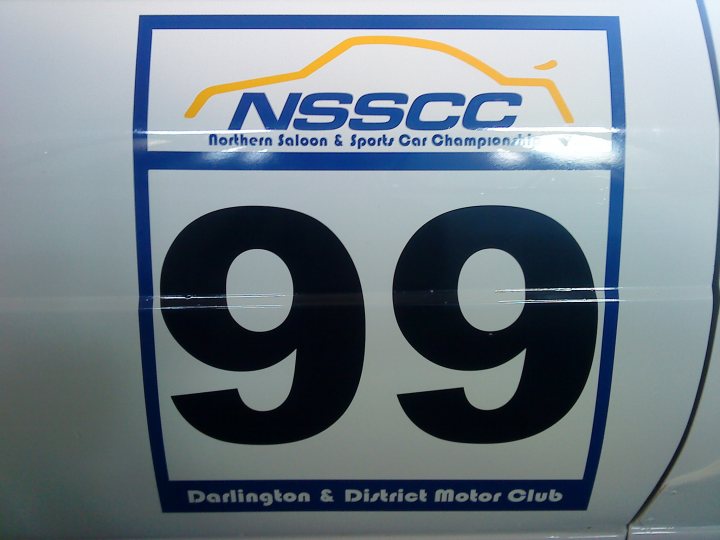 Saloon Northern Pistonheads - The photo showcases a number on a white car, which appears to be a sign or a logo. The number in view is "99." Above the number, there are texts that say "NSSCC Northern Saloon & Sports Car Club." The car is a DARLTON & District Motor Club. The background is blurred, emphasizing the white surface of the car.