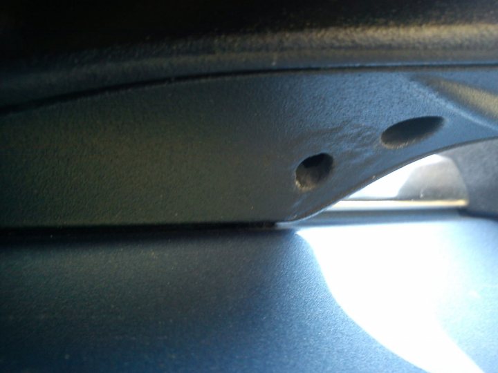 Pistonheads - The image captures a close-up view of a black car part, likely a glove box lid or a console cover, with a convex shape. Two circular details, possibly screws, are screwed into the part's body, creating a reflective surface that might catch the light inside the car. The photograph is taken in such a way as to enhance the reflection on the part, creating a contrasting interior light with the darker exterior environment. The focus is on the curvature of the car part's surface, emphasizing its shape and the gleam of the reflective surface.