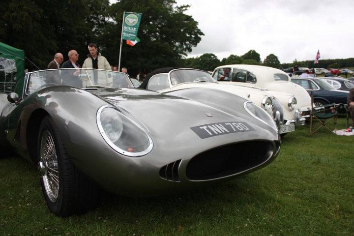 Anyone going to the Raby Castle car show 19th June? - Page 1 - North East - PistonHeads - The image captures a scene from a classic car show. Three vintage cars are parked in a neat row, their bodies gleaming under the light. The car closest to the camera is a striking silver model, bearing the license plate "TIN 782". The other two cars are a charming white, their presence adding to the vintage charm of the scene. A crowd of people is gathered around, their faces filled with admiration and interest as they inspect the cars, exploring the hoods and making notes. A large green tent stands out in the background, providing a contrast of colors to the otherwise monochromatic scene. The entire event is set against the backdrop of a grassy field, enhancing the outdoor atmosphere of the car show.