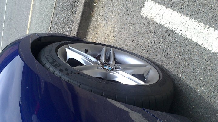 A close up of a toilet in a parking lot - The image captures a scene of road damage, with a focus on the wheel of a blue car. The wheel is tilted and sinking into a large pothole that has compromised the road surface. The blue color of the car is prominent, highlighting the worn and damaged nature of the road. The perspective of the image suggests it was taken from beside the vehicle, with the textured pattern of the tarmac leading the eye towards the damaged area where the wheel is located. The image conveys a state of repair or maintenance necessary due to road conditions.