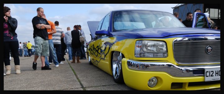 Chevy Pistonheads Truck - The image captures an outdoor car show where the main focus is a customized truck painted in vibrant shades of blue and yellow. The truck is positioned on a concrete surface, and its design appears to be a blend of car and truck elements, set against the backdrop of a crowd who are gathered around the vehicle.

The onlookers, dressed casually, appear interested in the truck's design and color. Some are standing closer to the vehicle, while others are a bit further away. The truck's design, with its lowered front, suggests a custom or modified theme.

The setting seems to be a street or a large pavement area, with clear skies overhead, indicating it might be a sunny day. The crowd's casual attire suggests a relaxed and leisurely event. The image conveys a sense of community among the truck enthusiasts.