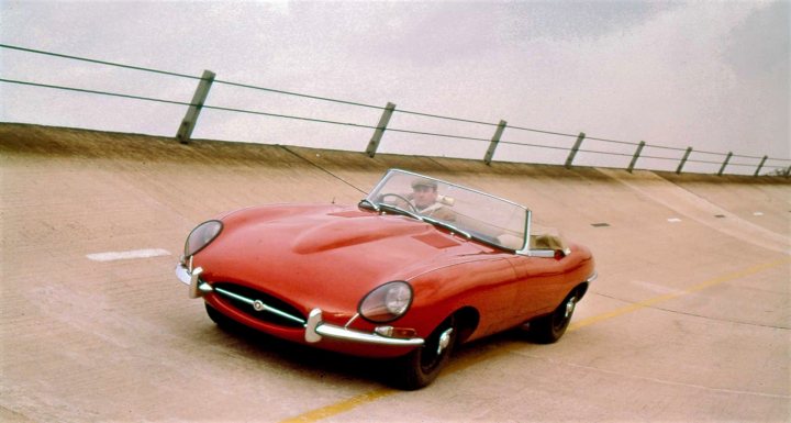 Pistonheads - The image is a split photograph. On the left side, there is a small red car on a highway with a metal railing in the background, under an overcast sky. On the right side, featuring the upper half of the photo, there is a person sitting in the driver's seat of the same red car, which appears to be moving at high speed along the highway. The car's design suggests it might be from the 1960s or early 1970s. The individual seems focused on the road ahead, and the image has a vintage feel to it due to its composition and subject matter.