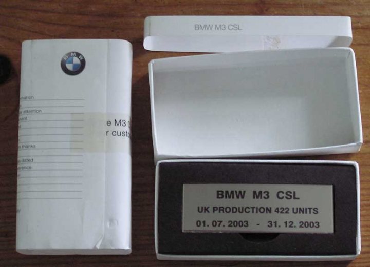 Csl Pistonheads Plaque - The image presents a unique scene of an open BMW car box and its corresponding styrofoam box. The BMW car box is a rich shade of brown with a white interior. Inside, we can see a white sheet laying flat, followed by an unusually empty space that extends quite high up the box. Adjacent to this container is a small black box. This box is adorned with black and white writing, providing specific information about a BMW M3 CSL. The visible text reads "BMW M3 CSL UK Production 422 Units 01.07.2003 - 31.12.2003", suggesting a special edition model of the BMW M3 CSL.