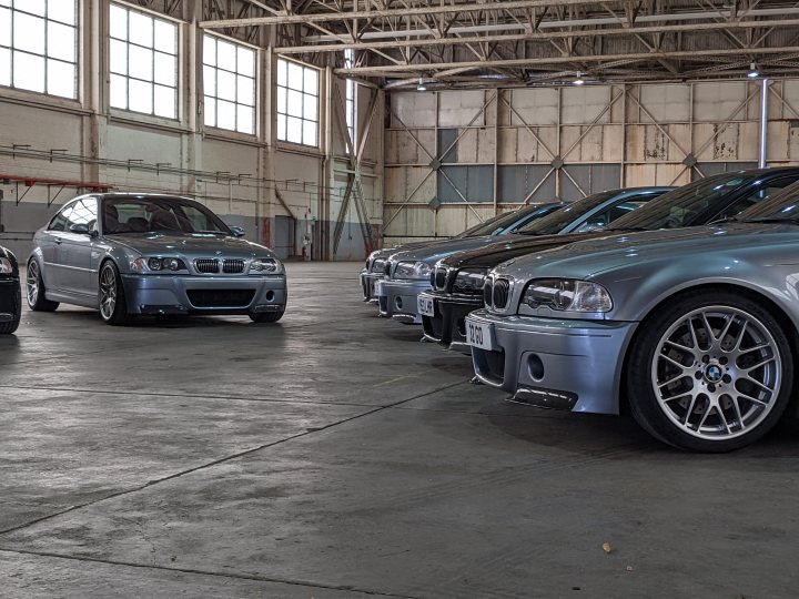 M3 CSL and M5 - Page 6 - Readers' Cars - PistonHeads UK - The image shows an indoor setting, likely a warehouse or garage, with several cars neatly parked side by side. These cars vary in model and color, suggesting they may be on display or being prepared for sale or exhibition. In the background, there's a large window that allows natural light to enter the space. The floor is concrete, typical of an industrial setting, and the overall impression is one of orderliness and cleanliness.