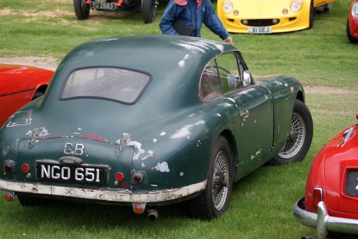 Is this wrong or so right??? - Page 1 - Classic Cars and Yesterday's Heroes - PistonHeads - This image features a vintage green car parked on grass. The vehicle, with the license plate "NGO 651", appears to be in a car show or collection setting. There are numerous other cars, both vintage and modern, visible in the background, suggesting the car is part of a larger gathering. The car seems to be in good condition, despite minor paint damage and rusted areas, indicative of wear over time.