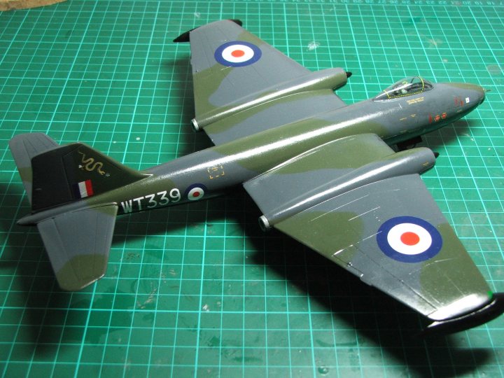 Pistonheads - The image showcases a model airplane, painted in a realistic shade of green reminiscent of a wartime British aircraft. Clearly visible on the tail is the emblem of the Royal Air Force, a stylized crown and lion, reflecting its origin. The plane is exhibited with impressive detail on the wings and tail, indicating it is a meticulously crafted model. It rests on a surface laid out with a grid pattern, suggesting that this could be a depiction of an aircraft at a scale model event or exhibition.