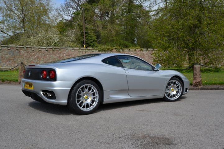 360 thread - Page 1 - Ferrari V8 - PistonHeads - The image shows a silver Audi sports car parked on a paved surface. The car's sleek design features a wide stance with large wheels, and the body has a visible reflective surface that suggests it might be a convertible. Natural light is evidently hitting the vehicle, indicating it's either early morning or afternoon. In the background, there's a brick wall, creating a contrast between the architecture and the modern style of the sports car.