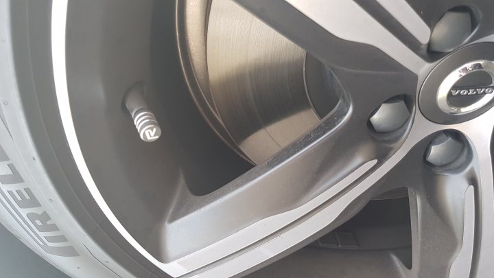 The Volvo S90/V90 lease thread - Page 153 - Volvo - PistonHeads - The image provides a detailed view of the wheel of a car. The wheel cap is prominently displayed in the center of the rotation, featuring the Volvo logo. The spoke housing, painted in a matte black color, has a distinct silver metal rim. The lug nuts, also finished in silver, secure the wheel in place. The overall image provides a technical and holistic perspective of the car's mechanical parts.