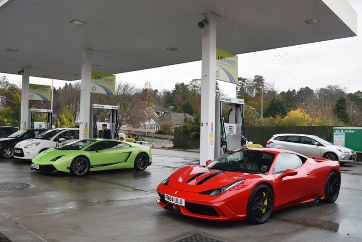 Speciale arrived today - Page 1 - Ferrari V8 - PistonHeads - The image captures a scene at a gas station, featuring three exotic sports cars. A red Ferrari is parked prominently at one of the pumps, its glossy paint standing out against the concrete of the station. To its left, a green Lamborghini and a white Lamborghini are also parked, both adding to the luxurious ambiance of the scene. The cars are neatly lined up, suggesting that the driver of the Ferrari might be associated with these two Lamborghinis. The gas station itself appears well-maintained, providing a fitting backdrop for these high-end vehicles.