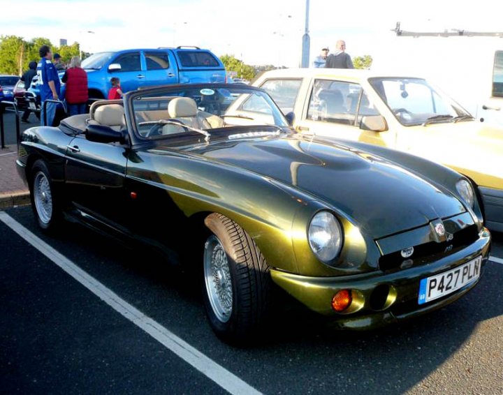 Pistonheads - The image features a classic British sports car, which is particularly notable due to its metallic green finish. This piece of automobile history has shifted the focus of the scene to itself. The car is parked in a lot with other vehicles around it, indicating a public space. A few pedestrians can be seen around the car, adding a human element to the scene. The license plate of the sports car reads "PO47 PLO", providing a unique identifier for this automotive icon.