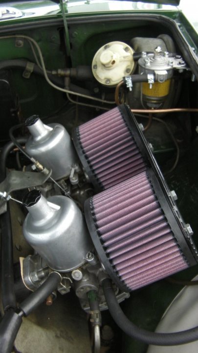 Pistonheads - The image reveals the complex interior of an old car, showcasing the mechanical components of a classic engine. A prominent feature is a silver machine, possibly an oil or gas pump, located centrally beneath the closed hood. The car's interior paint is beginning to wear, hinting at its age and history. The machine is connected to various hoses and wires, indicating its integral role in the car's operation. The color scheme of the image is dominated by shades of blue and red, which add depth and contrast to the scene.