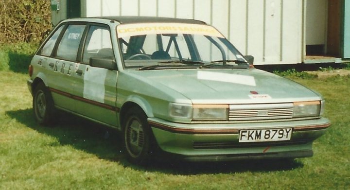 Tell me about British Leyland  - Page 23 - Classic Cars and Yesterday's Heroes - PistonHeads - The image features an old, vintage car parked on grass. The car is predominantly green and appears to be a hatchback with some modifications or repairs, as indicated by the patched-up areas on its body. There's a small sign in the back of the car that reads "69," perhaps indicating the year or model of the vehicle. In the background, there's a fence, suggesting this scene might be taking place in a rural area or a park. The overall impression is that of an antique vehicle being showcased outdoors.