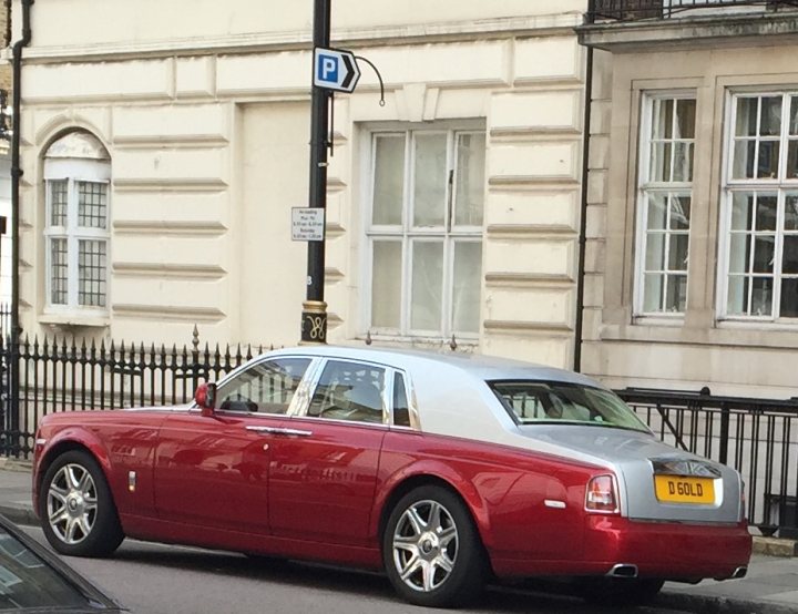 What C124PPY personalised plates have you seen recently? - Page 201 - General Gassing - PistonHeads - This image depicts a luxury car parked on a city street. The car is a vibrant red and is a model that resembles a classic Bentley. It has a shiny exterior with distinct chrome details and the car's license plate is clearly visible. Surrounding the car are classic city buildings with large windows, and there is a parking sign indicating a public parking area on the sidewalk. The photo captures a typical urban setting, with a sense of order and safety.