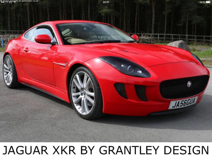 Xkr/Ftype lovechild ! - Page 1 - Jaguar - PistonHeads - The image displays a sleek, red Jaguar XXR sports car in a static outdoor setting. The car is parked on a paved surface, possibly a parking lot or driveway, with the engine cover not closed, suggesting recent use. The vehicle has a polished finish and distinct features such as aerodynamic vents, large wheels, and a sporty design. The setting includes a backdrop of sparse, natural vegetation, indicating a rural or semi-rural environment.