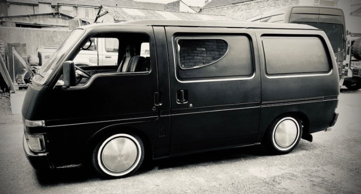 A black and white photo of a bus parked in a parking lot