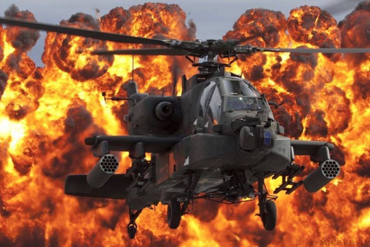 Post amazingly cool pictures of aircraft (Volume 2) - Page 203 - Boats, Planes & Trains - PistonHeads - The image captures an intense scene of a helicopter flying above a fiery landscape. The helicopter, with its large body and propellers, is centrally positioned in the frame, appearing to be a military helicopter. It's surrounded by an expansive horizon, drawing the viewer's attention to the impressive arsenal of flared munitions beneath it. These munitions, shaped like spheres, have been ignited and are now engulfed in flames, creating a bright and fiery display. The orange and yellow hues of the fires contrast sharply with the helicopter's metallic colors, emphasizing the power and heat emanating from the explosions. The image conveys a sense of action and power, capturing a moment of high-stakes military activity.