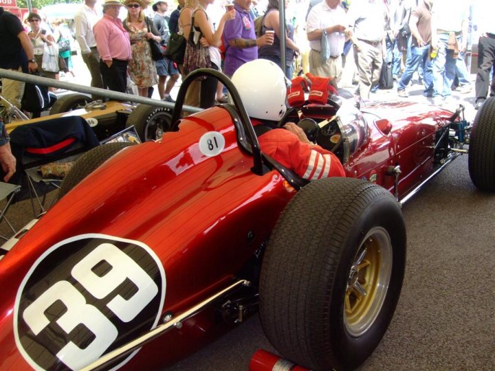 Goodwood FoS pics / videos - Page 1 - Goodwood Events - PistonHeads - The image captures a vibrant scene at a car show. The red car, adorned with a large number 39, is the focal point of the frame. Its sleek design and shiny surface reflect the ambient light, adding to its allure. The presence of other people in the background, mingling and enjoying the event, further enhances the atmosphere of the show. The red car, with its eye-catching color and prominent number, stands out amidst the sea of people, making it a memorable sight.