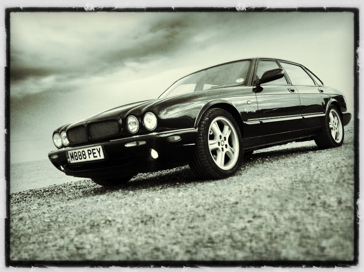 Local photo locations - Page 1 - East Anglia - PistonHeads - The image captures a scene of a black, classic sedan parked on a gravel road. The car's details are crisp and the background features a dramatic sky filled with clouds. The vintage model of the car, along with the text "Auto Home" on its registration plate, gives the image an old-fashioned feel. The area around the car is quite empty, with no other objects or people visible, which puts the focus solely on the car.