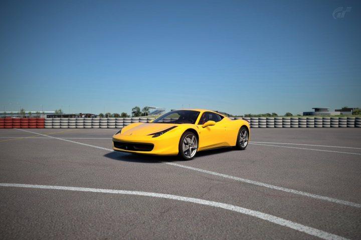 Gran Turismo 6 picture thread - Page 3 - Video Games - PistonHeads - This image features a bright yellow sports car on a track that is surrounded by a series of tire barriers. The car is positioning itself near the left side of the image, and it appears to be in motion, as suggested by the position of its passenger side rear tire. The environment outside the track includes a green, grassy area. In the top right corner, there is a watermark of the initials "GTR." The setting suggests a racing event or a practice session.