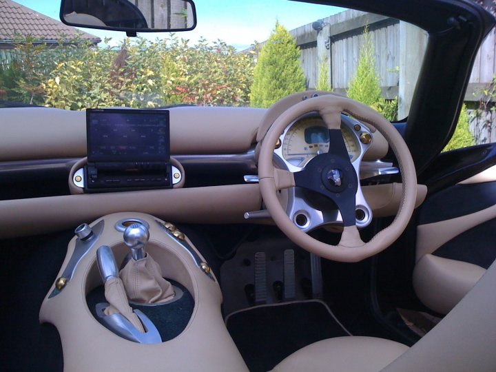 Pistonheads - The image captures the interior of a luxurious vehicle, where features like a sports steering wheel, a security system, and a GPS device are installed. From the driver's perspective, the steering wheel is prominently featured, indicating the road lying ahead. In the midst of the scene is a black seat for the driver, inviting and comfortable, with a foot pedal positioned adjacent to it. The dashboard, a blend of sophistication and modern technology, is topped with a stack of useful but stylish accessories that add to the overall sleek look.