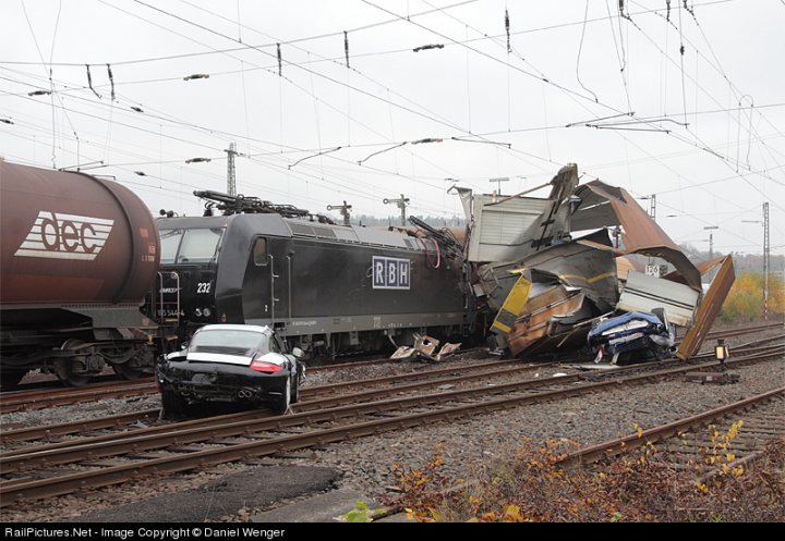 Bumped Bought Dealer Pistonheads - The image depicts a serious train derailment. A train, a railcar, and two cars have been involved in the incident. The overturned railcar is on fire, with the surrounding environment also showing signs of damage. Emergency response vehicles, identified by the letters Bureau of Emergency Combatants (BEEC), and personnel are present on the scene, and power lines are also visible in the background.