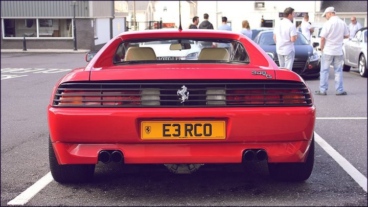 Ferrari 348 chit chat - Page 1 - Ferrari V8 - PistonHeads - The image portrays a vibrant and dynamic street scene. At the center of the frame is an eye-catching red sports car, parked in a way that aligns with the parallel lines of the parking space. The car, with its sleek design and distinctive yellow license plate, seems to be the main subject of the image. Surrounding the car are blurred figures of people and cars, creating a sense of depth and activity in the background. The composition of the image suggests that it was taken during the day, with natural and artificial light illuminating the scene from different directions. The image captures the essence of urban life, where every element has its own story to tell.