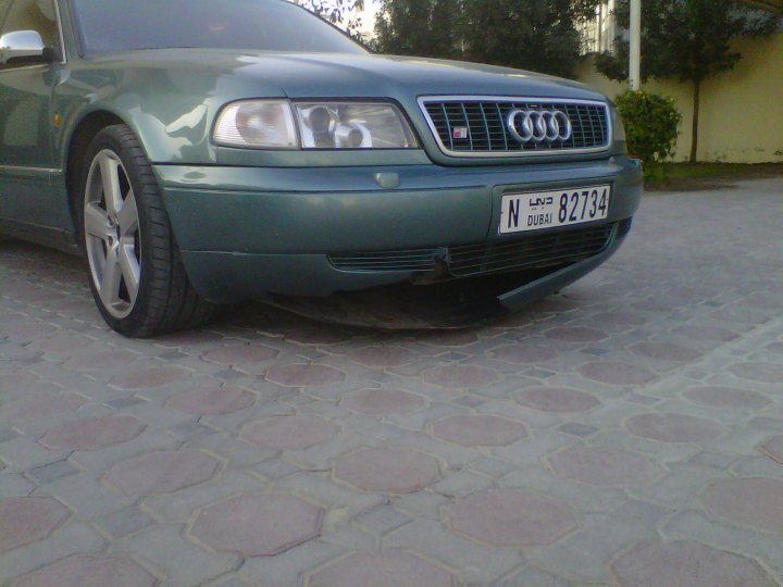 What's Red and White...... - Page 1 - Middle East - PistonHeads - The image shows a close-up view of the front of an Audi car parked on a red brick paved surface. The Audi emblem is prominently displayed, and the car features a European-style license plate with the word "DUBAI" on the back of the car, as well as on the license plate. The vehicle has a dark green exterior, and there's a slight angle to the shot, making the front passenger side more visible than the driver's side. The brick pavement has a diamond pattern.