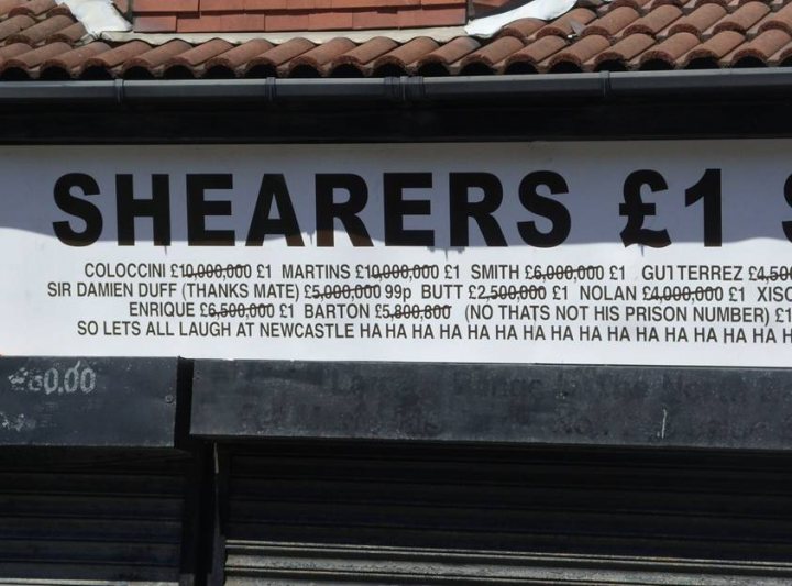 Pistonheads - The image features a white sign with black lettering attached to a building's exterior wall. The sign is advertising "sharers" priced at one pound. It lists different types of sharers available, which include a variety of named beverages at varying volumes and price points. Prices for a half-gallon range from one to two pounds, while a full gallon is priced up to four pounds. The sign is adorned with multiple exclamation points to emphasize the sale's details.