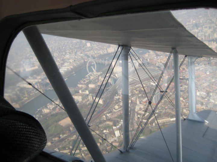 Post amazingly cool pictures FROM aircraft. - Page 2 - Boats, Planes & Trains - PistonHeads - The image provides an aerial view, possibly from an airplane window, showcasing a large city with numerous defined trails and roads. The view is blocked by the wing and poles of an airplane, which may limit the scope of the view. The photo is taken from an elevated position, possibly from a higher level of a building or a life-preserver coming down from the sky, judging by the intact belt and the airplane structure. The perspective is so high that it gives a comprehensive look at the cityscape.