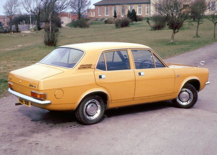 You're all doing so well.... - Page 1 - Classic Cars and Yesterday's Heroes - PistonHeads - The image shows a bright yellow compact car parked on the side of a well-maintained road. The car is facing towards the left side of the photo, and is the main subject of the image. Behind the car, there is a hedge and a grassy area, giving a sense of a suburban or rural setting. In the background, partially obscured by the car, there is a two-story brick building. The car appears to be in good condition, suggesting it may be a well-maintained classic vehicle. The photograph has a vintage quality to it, indicating it may have been taken several decades ago.