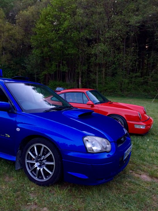 I am back!!!!! - Page 3 - Subaru - PistonHeads - The image showcases a serene wooded setting, with three cars parked side by side on a grassy field. The cars are an eye-catching mix of two red sports cars and one blue muscle car, all positioned perpendicular to the viewer. The vehicles are facing the same direction, adding to the symmetry of the scene. The woods in the background provide a natural and tranquil backdrop, enhancing the overall ambiance of the image.