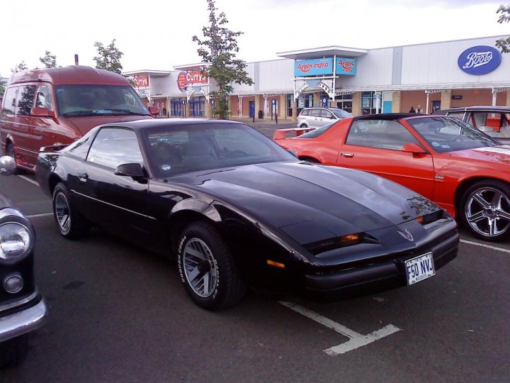 Cruisemeet Edinburgh Pistonheads - In the heart of a bustling parking lot, a classic black sports car steals the spotlight. It's parked neatly between two other vehicles, a striking red wagon and a sleek black muscle car. The lot is nestled right in front of a Walgreens, with a Supercuts salon just behind and a Burger King restaurant nearby. The scene is a testament to the active and vibrant atmosphere of everyday American life.