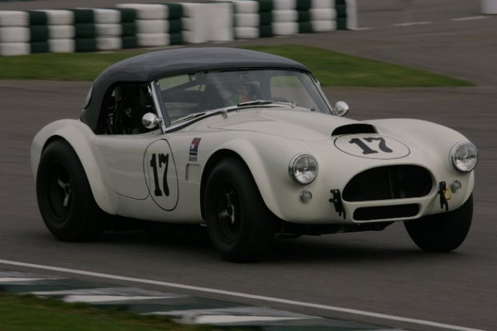 Masters race series, 10th March - Page 1 - Goodwood Events - PistonHeads - The image shows a grey distressed convertible racing car on a race track lined with white barriers. The car is marked with the number 17 and has a black number 10 on the side plus other branding details. The rear bumper has a distinguishing red stripe. The vehicle has a two-door, dark-toned color scheme and a rooftop suspension. The track appears to be wet, as evidenced by the reflections cast on the ground.