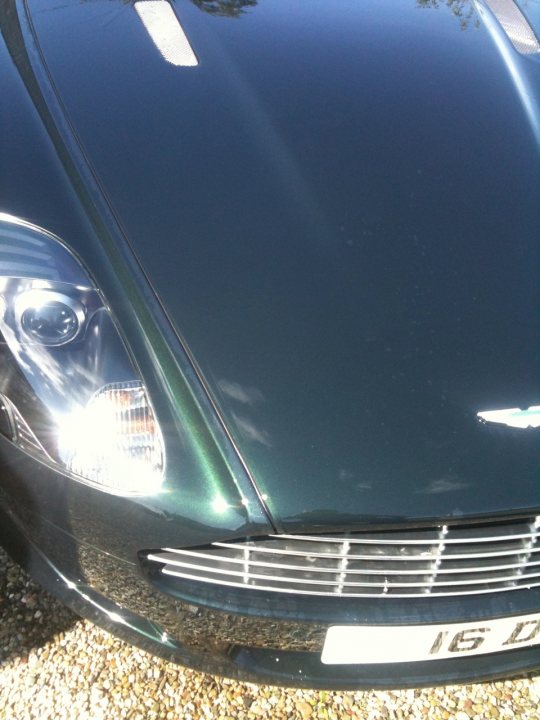 A close up of a car on a city street - Pistonheads - The image shows the front grille of a car, which is dark in color, possibly black or a deep blue. The grille is shiny and appears to be well-maintained, indicating that the car itself might be in good condition. The design features straight and curved lines with a prominent vertical groove. The hood of the car is reflective, suggesting that the photograph was taken with sunlight on a bright day, which casts light and shadows on the vehicle's surface. The overall style of the image is a close-up, portrait-oriented photograph focusing on the front of the vehicle.