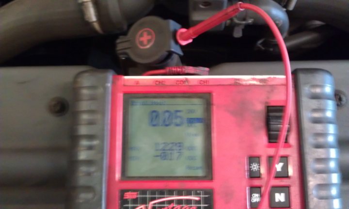 Pistonheads - The image shows a red display device with various buttons and readings, connected to a mechanical component, possibly part of a vehicle's engine. There is a speedometer reading of 0.5 kph (kilometers per hour) and a temperature measurement of -9 degrees Celsius. The device's interface appears to be digital, with several function buttons and a screen displaying the indicators. The mechanical component is situated in a dark environment, with the device attached via a cable, suggesting a diagnostic or monitoring role.