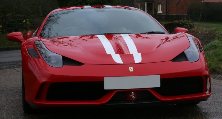 A red double decker bus parked in a parking lot - Pistonheads - The image features a snubbed nose car with a vibrant red sportscar body. The car appears to be a Ferrari, identified by the emblem on the front and the presence of the "Prancing Horse" logo on the car's front bumper. The hood of the car shows a white stripe, and the front features small round headlights. The car is parked on a paved surface, and the background reveals a residential setting with houses and greenery.