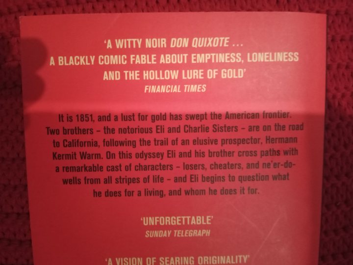 Books - What are you reading? - Page 417 - Books and Literature - PistonHeads UK - The image features a book cover with a predominantly red background. The title of the book is prominently displayed in white, serif font at the top: "a witty noir don quixote". Below the title, there is a subtitle that reads: "blackly comic fable about emptiness, loneliness, and the hollow pursuit of gold".

Additional text on the cover provides information about the book's author and content. It states: "Is it 1893 and lust for gold has swept the American frontier? The road to California leads to an exclusive proprietor of the famous HELEN GOLD RUSH". The author is identified as "Kermit Warm" with a note indicating that he has written several plays.

The bottom of the cover features a quote from The Sunday Times, which praises the book as a remarkable and entertaining work: "A vision of searing originality." This text is in white, capital letters, emphasizing its importance as an endorsement for potential readers. The overall style of the image suggests that it is likely a promotional photograph or graphic intended to showcase the book's cover design and entice potential buyers with the promise of a humorous and thought-provoking reading experience.