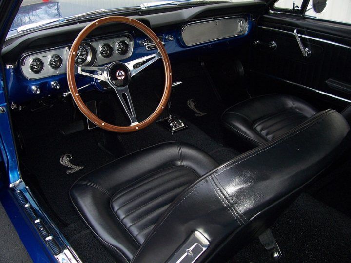 New owner what do you guys think. - Page 1 - Mustangs - PistonHeads - This image shows the interior of a classic car, characterized by a vibrant blue body and contrasting, black leather seats. The steering wheel, with its chrome exterior, is the focal point of the image, suggesting the perspective is from a seated position inside the car. The seats are plush and well-maintained, indicative of a car in good condition. In the background, the observer might glimpse the dash, which could contain gauges and other controls typical of classic cars.