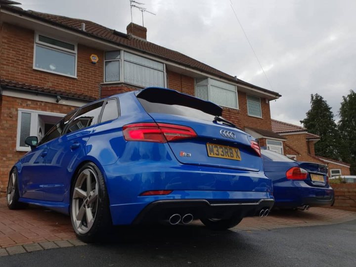 HELP - was sold a cat A/B car - Page 6 - General Gassing - PistonHeads - The image is a photograph of two blue Audi RS5 cars parked side by side on a residential street. They have tinted windows and customized body kits with visible spoilers, akin to a wide-body or track style modification. The vehicles are positioned in front of a house with a brick facade. The sky is overcast, suggesting the photo might have been taken during an overcast day. The image also contains watermark text at the bottom right corner, indicating the photographer's mark on the picture.