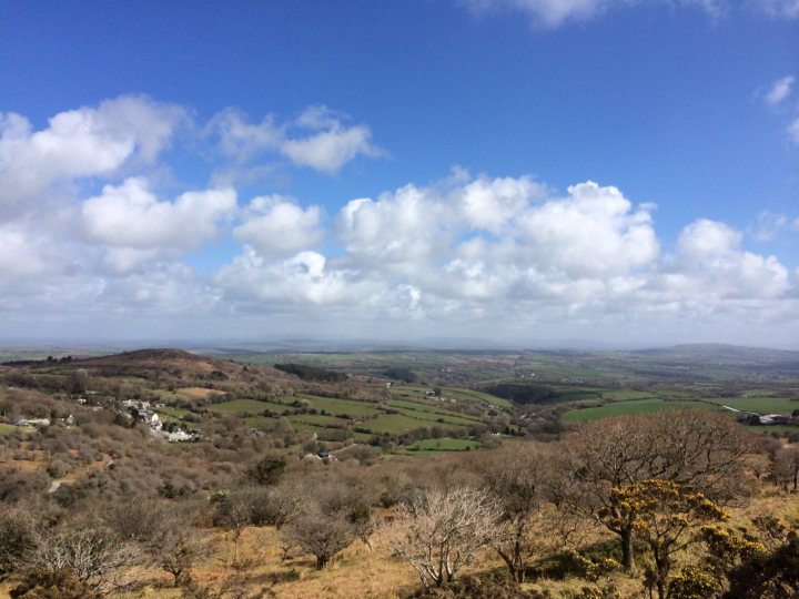 The "Photos From Today's Ride" thread... - Page 113 - Pedal Powered - PistonHeads - This image showcases a breathtaking panoramic view of a landscape. The foreground is dominated by rolling hills with patches of green grass and sparse patches of brown color, indicative of the Earth's varying seasons. As our eyes move towards the horizon, the landscape transitions into more rugged terrain. The hills become steeper and denser, giving way to a scattering of buildings at the base. These buildings appear to be small structures, possibly houses or barns, set against a backdrop of a vast expanse of clear sky. The entire scene is bathed in natural light, rendering the colors of the landscape with a vibrancy that brings the scene to life.