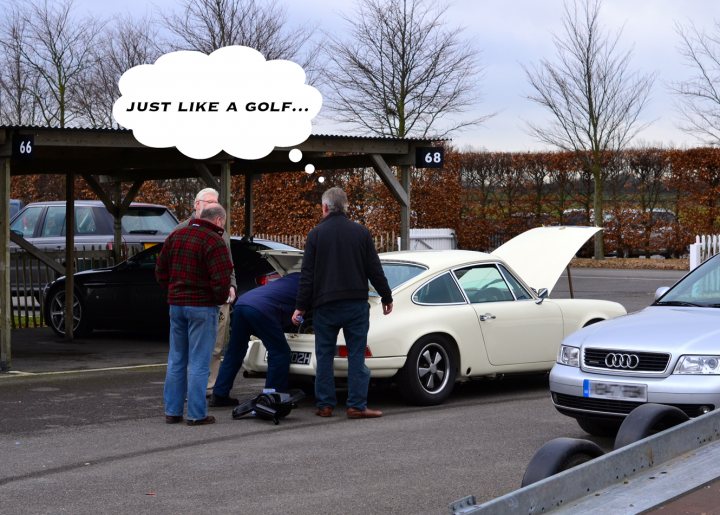 Robert Barrie Track Day 24th Feb Goodwood - photos - Page 1 - South Coast - PistonHeads - In the image, three men are gathered around a white VW Beetle under a parking covering with the hood open. The men appear to be in a parking lot, as evidenced by the other cars parked in the background. The most striking feature of the image is the text bubble floating above the Beetle, which playfully reads "just like a golf. ...". The location and the vehicle suggest a casual, social situation, perhaps in a campground.