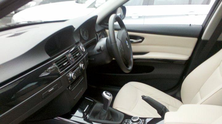 Pistonheads Efficient Dynamics Bmw - The image shows the interior of a sports car with a predominantly white color scheme. The driver's seat is in focus, with a steering wheel at the center. The dashboard features several controls along the lower edge. The passenger seat is visible on the right, partially out of focus. The car is parked in front of another vehicle, which appears to be a different model.