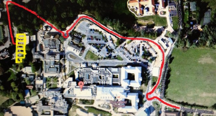 A sign that says `` <UNK> '' on a street corner - Pistonheads - The image presents an aerial view of a campus or a series of roads. A prominent feature is a long red line meandering across the landscape, likely indicating a route or a preferred path. "EP" is marked in red on the top part of the image, and there are yellow stop symbols at both ends, suggesting this is part of a traffic or road planning concentration. Additionally, there appears to be a forested area with a darker green cover to the left side of the image. The image seems to be a map or a graphic representation used for navigation or planning purposes.