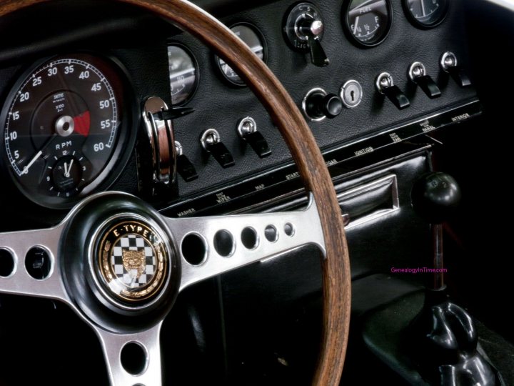 Best car dashboard - Page 16 - General Gassing - PistonHeads - The image showcases the interior cockpit of a vintage or classic vehicle, focusing on the steering wheel and dashboard. The steering wheel is black with a silver or metallic centerpiece, adorned with a round, badge-like emblem that resembles a checkered square. The dashboard features a combination of gauges with varying designs, both white and black with red and green pointers. The overall appearance suggests a nostalgic, luxurious California Type car, likely from the 20th century, characterized by its classic design and intricate detailing.