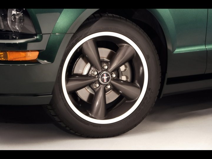 BULLITT WHEELS 2005 - Page 1 - Mustangs - PistonHeads - The image showcases a close-up of a tire on an SUV. The tire is of a large size, predominantly black with a silver rim. The design of the rim features a silver center and a black outer edge, giving it a sleek and modern appearance. The tire's pattern suggests it's designed for stability and performance on paved roads. The SUV the tire belongs to is predominantly green, with a smooth finish, and it can be inferred that it's either a car or an SUV given the visible wheel arch. The focus of the image is undeniably the tire, making it the main subject with the background slightly out of focus.