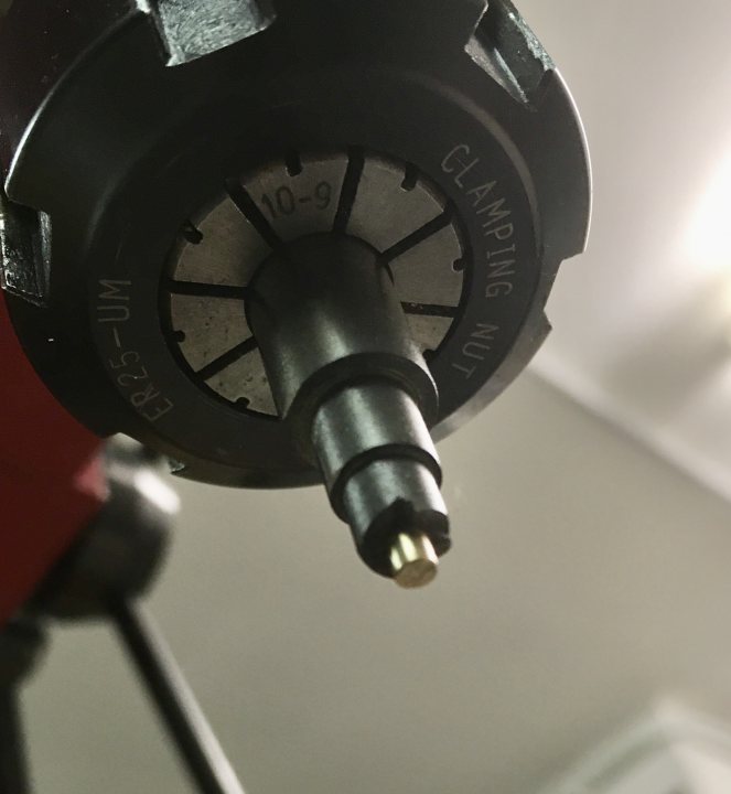 A close up of a clock on a building - Pistonheads - This image features a close-up view of a mechanical device, which appears to be an electric drill or screwdriver. The main focus is on the bit end, where a yellow electric drill bit is inserted into the chuck. The bit has numbers and measurements written around it, indicating its size, likely in millimeters. To the left of the drill, there's a red handle with a trigger-style switch, suggesting this tool is manually operated. The background is blurred but suggests an indoor setting. There are no texts visible in the image that provide additional context or information about the device.